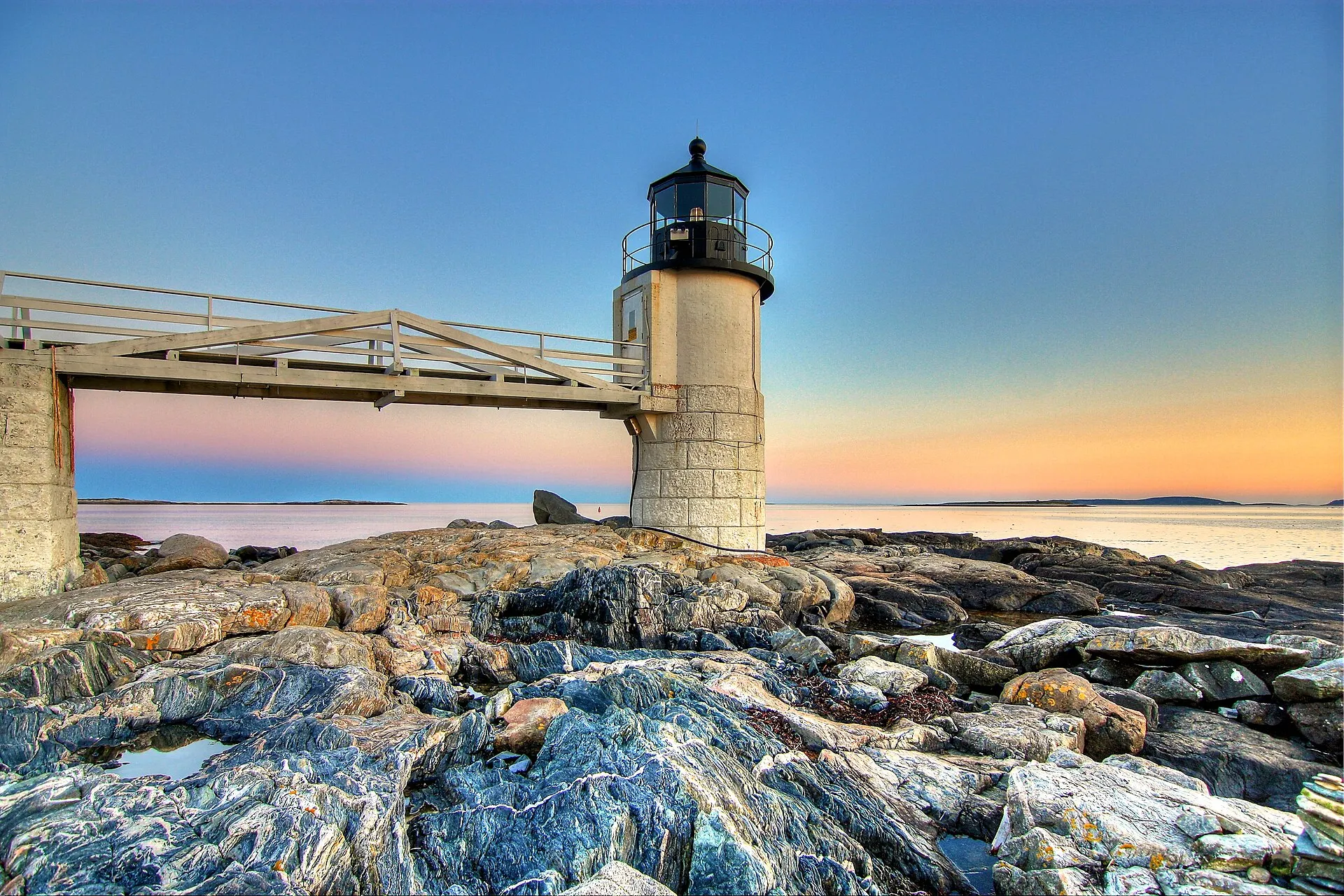 Marshall Point Light at sunset, with its wooden walkway running out to the granite tower