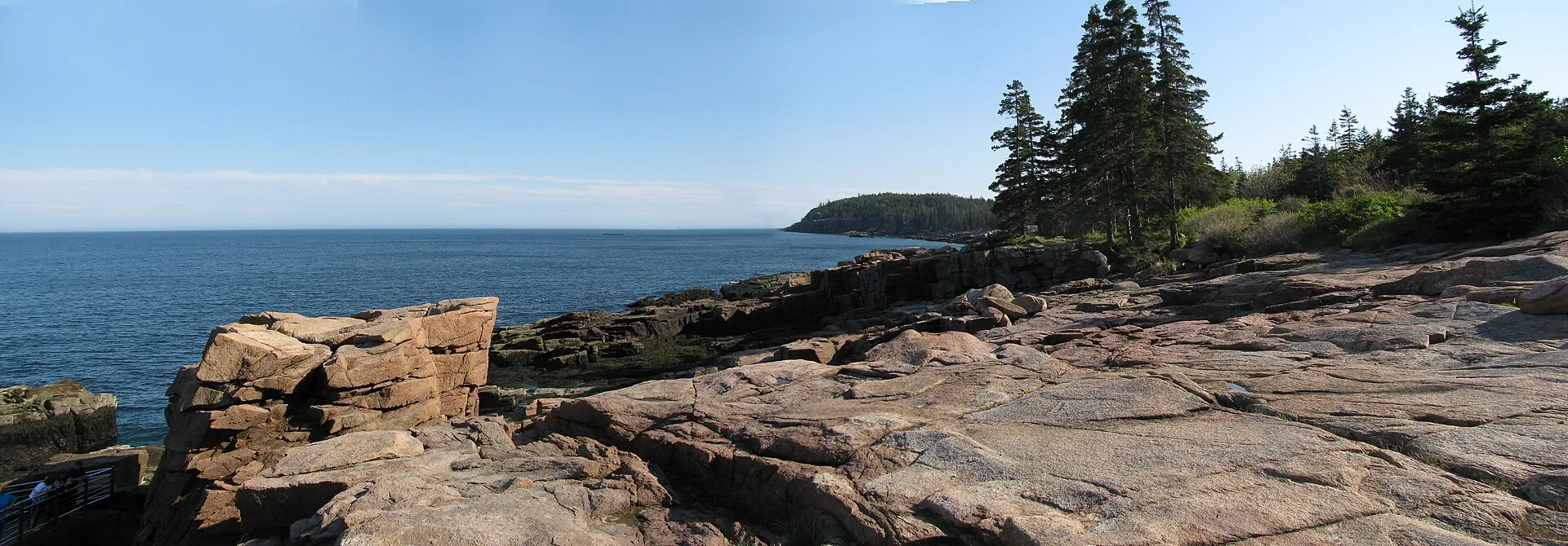 The pink granite ledges at Thunder Hole, looking south along Ocean Path toward Otter Cliff. Calm water like this is why NPS says the effect needs the right swell, one to two hours before high tide.